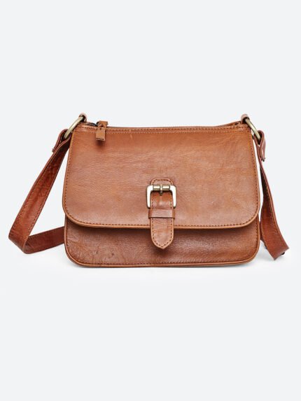 “Tan leather sling bag with gold hardware and front twist-lock closure against a light background.”