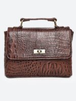 “Brown croc-textured leather sling bag with top handle and twist-lock closure.”