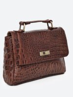 “Brown croc-textured leather sling bag with top handle and twist-lock closure.”