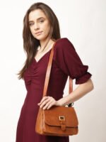 “Tan leather sling bag with gold hardware and front twist-lock closure against a light background.”