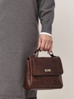 “Brown croc-textured leather sling bag with top handle and twist-lock closure.”